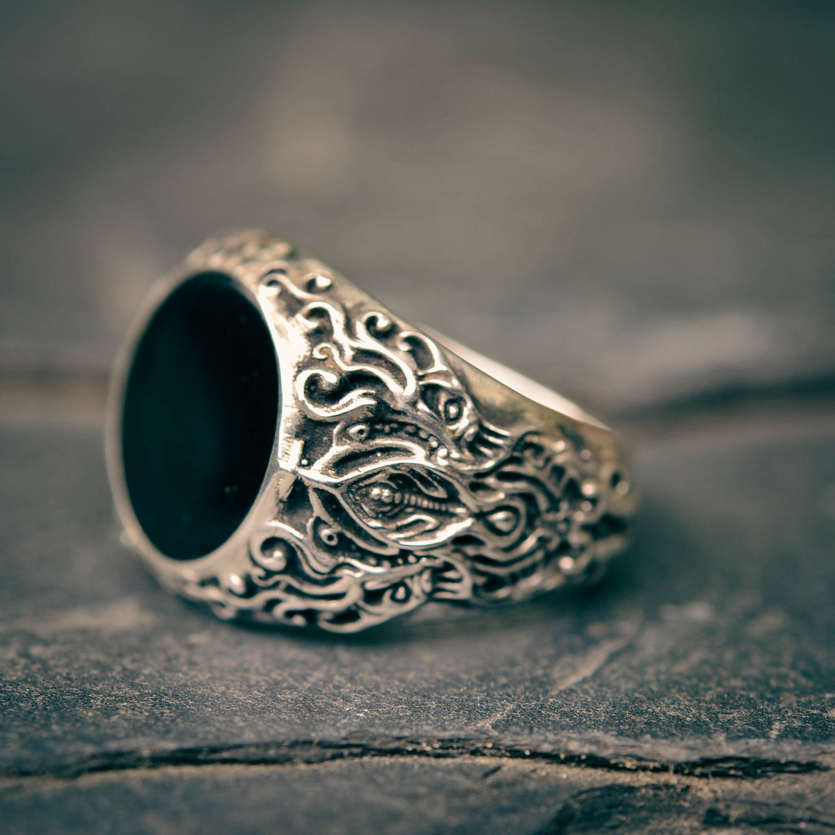 Silver ring with intricate designs on a textured surface