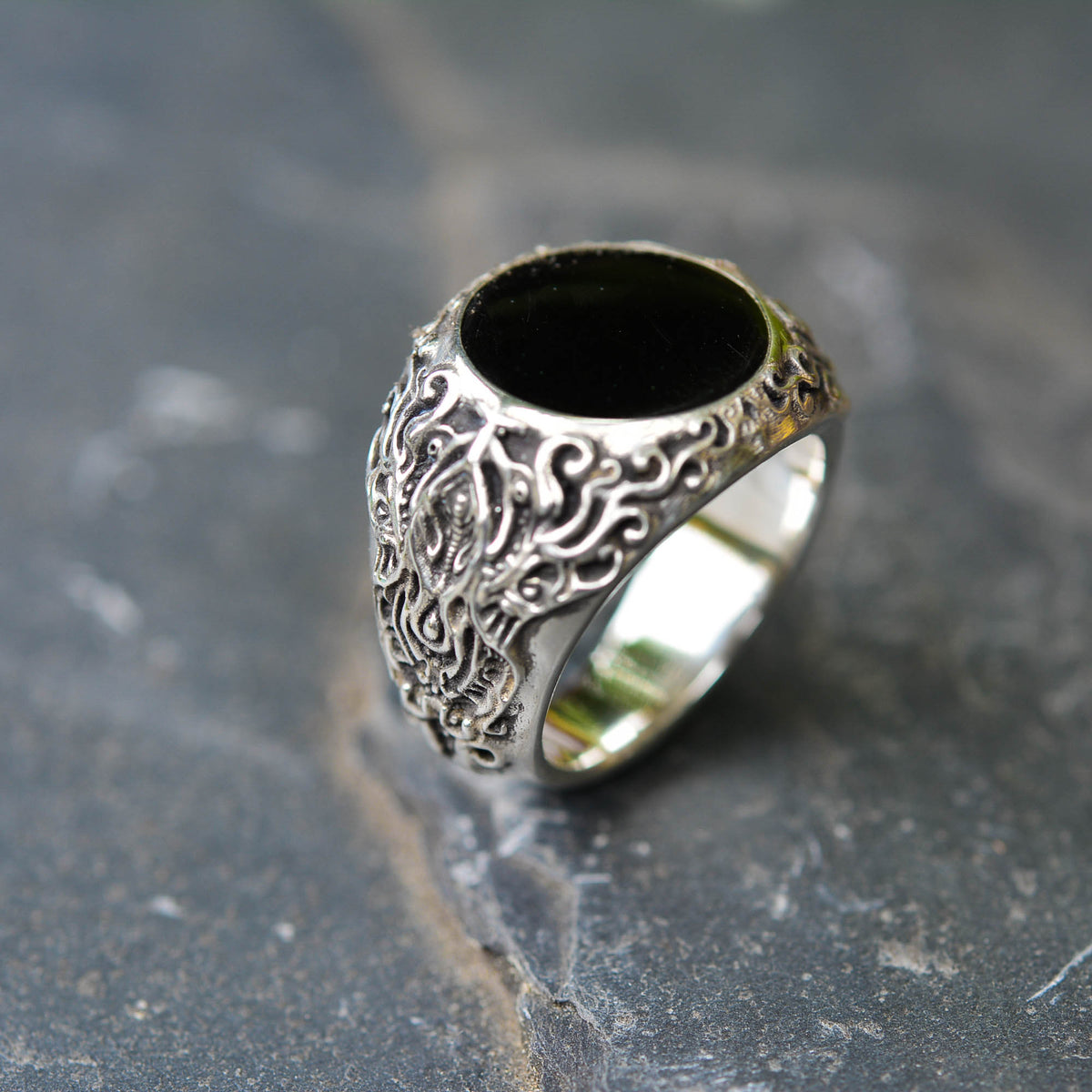 Silver ring with black stone on a textured gray background