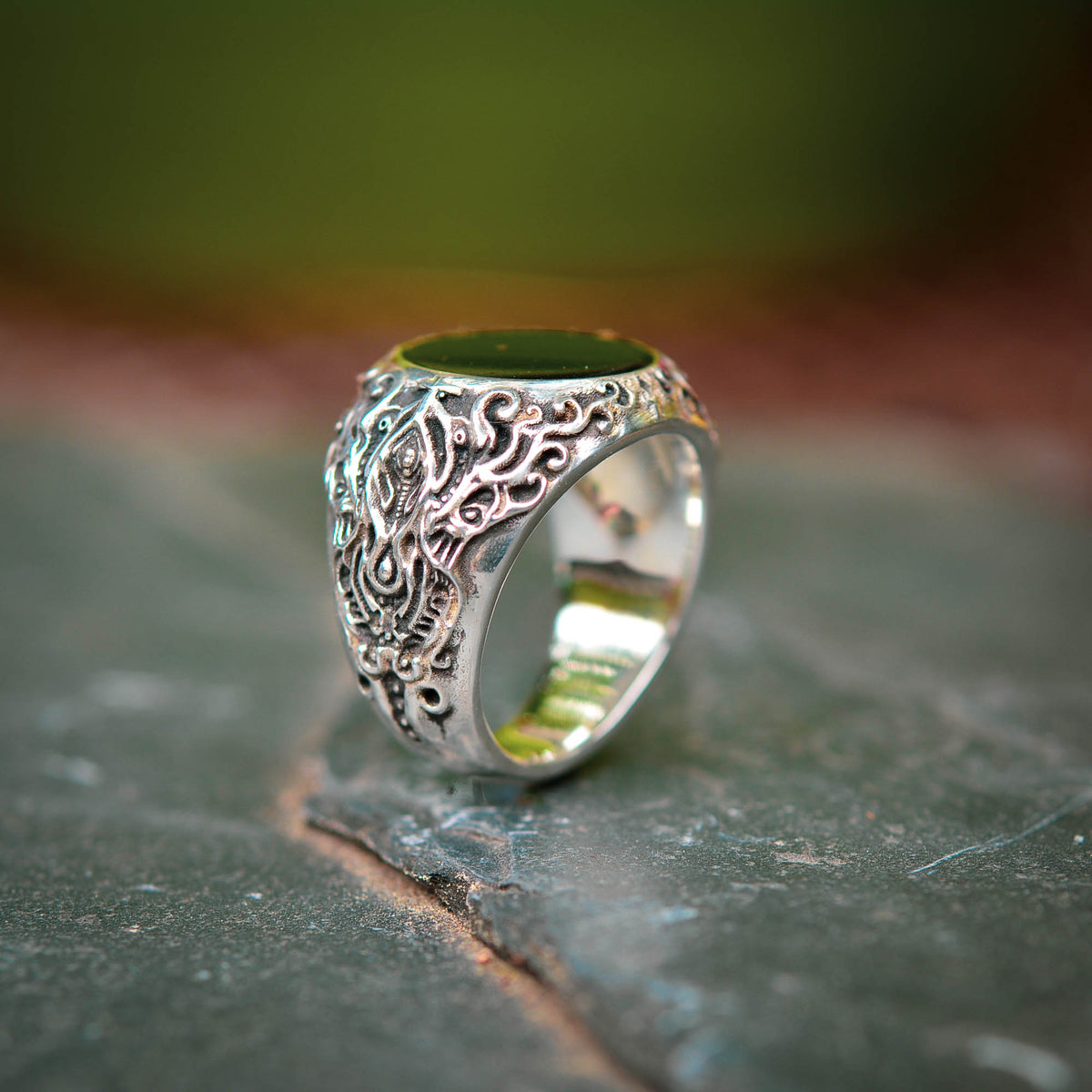 Silver ring with intricate designs on a stone surface.