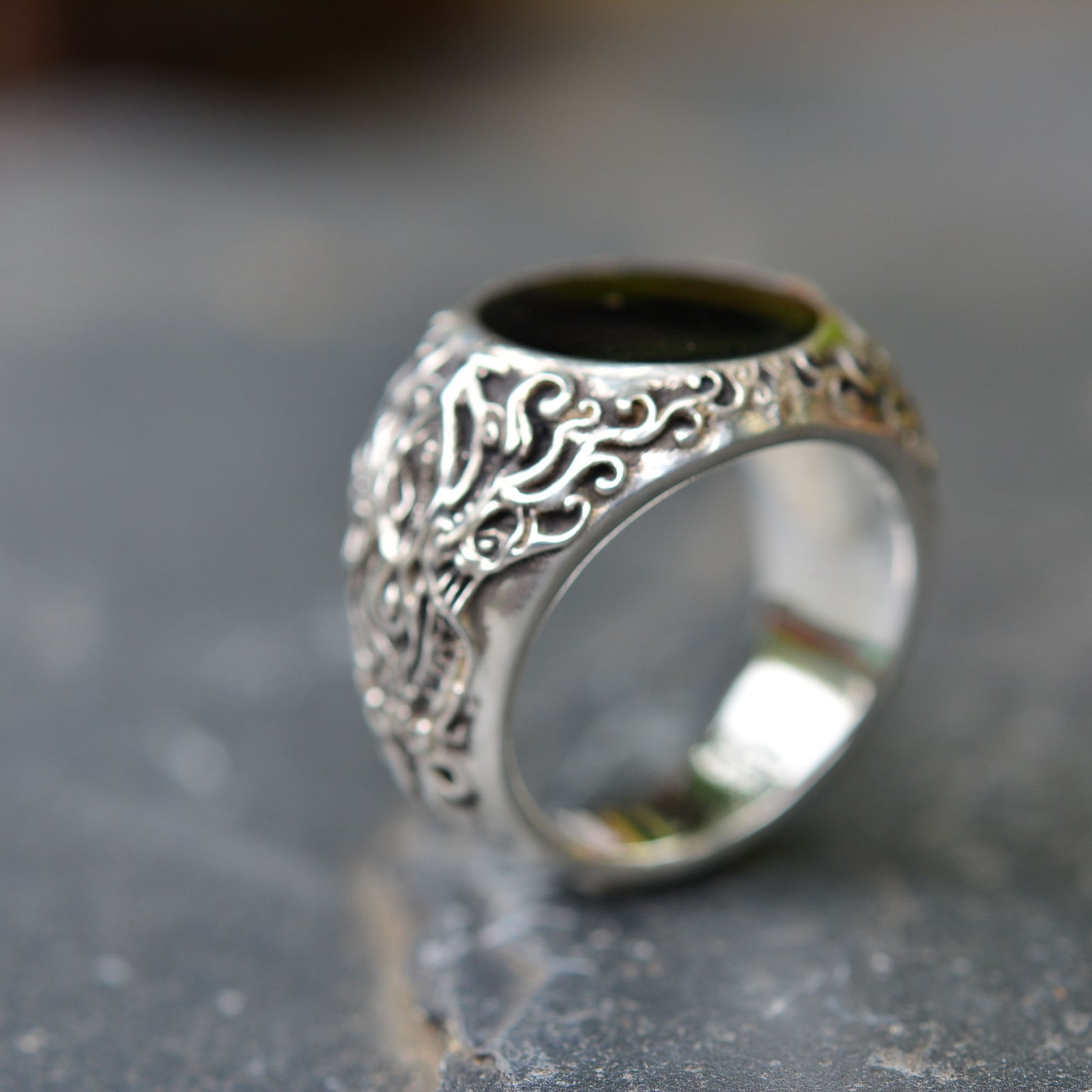 A large and sculpted sterling silver ring with a black hardened resin at the top