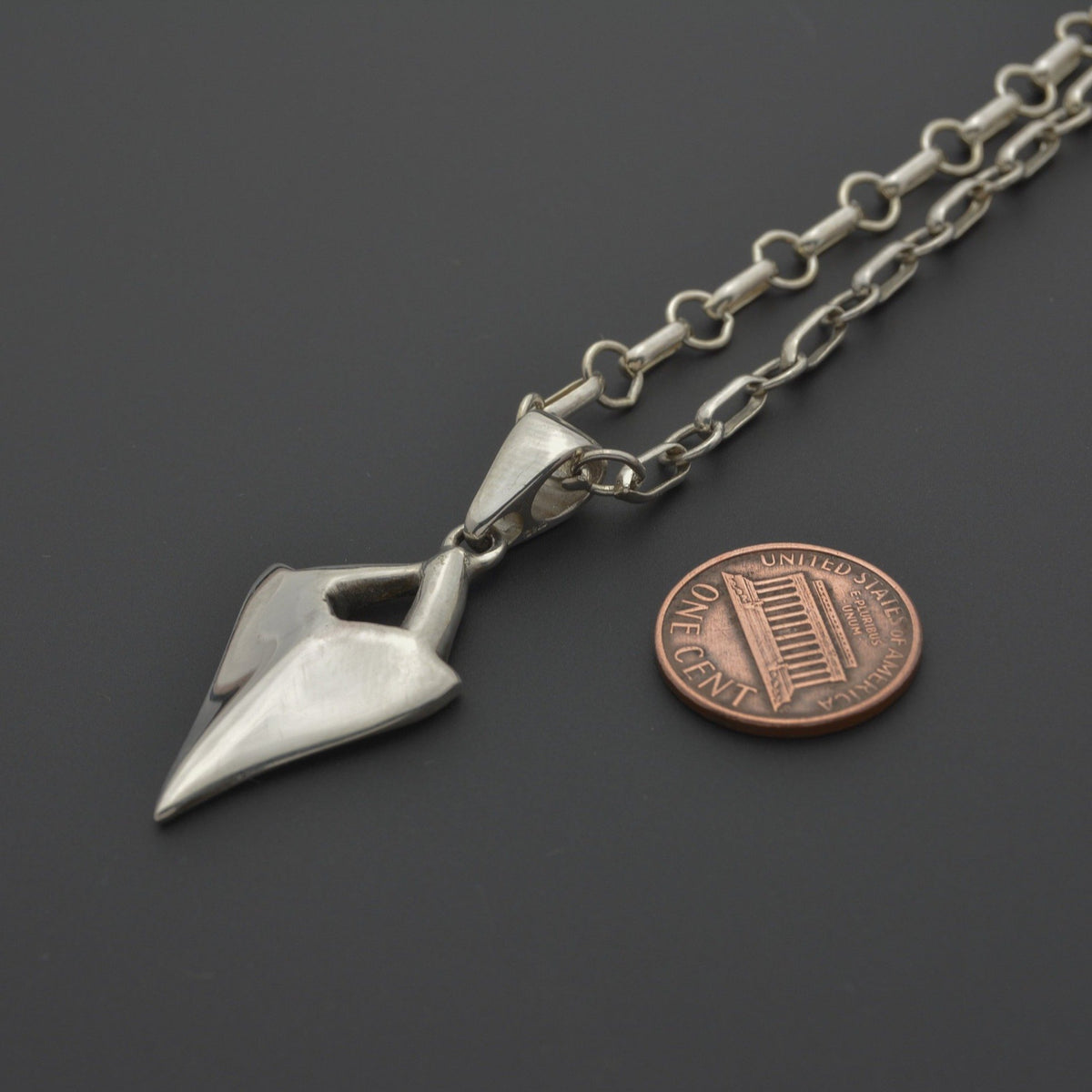 Shark tooth silver pendant next to a penny 