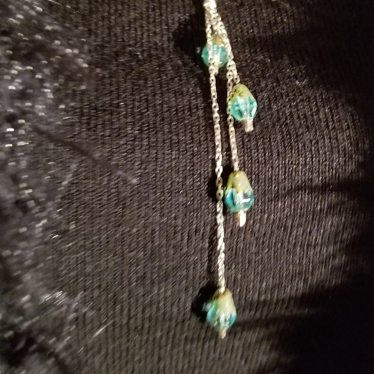 Emerald drops detail from silver cross pendant